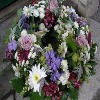 A medium-sized floral funeral wreath with a variety of flowers including pink roses and purple blooms Delivery Joannes Florist Winchester